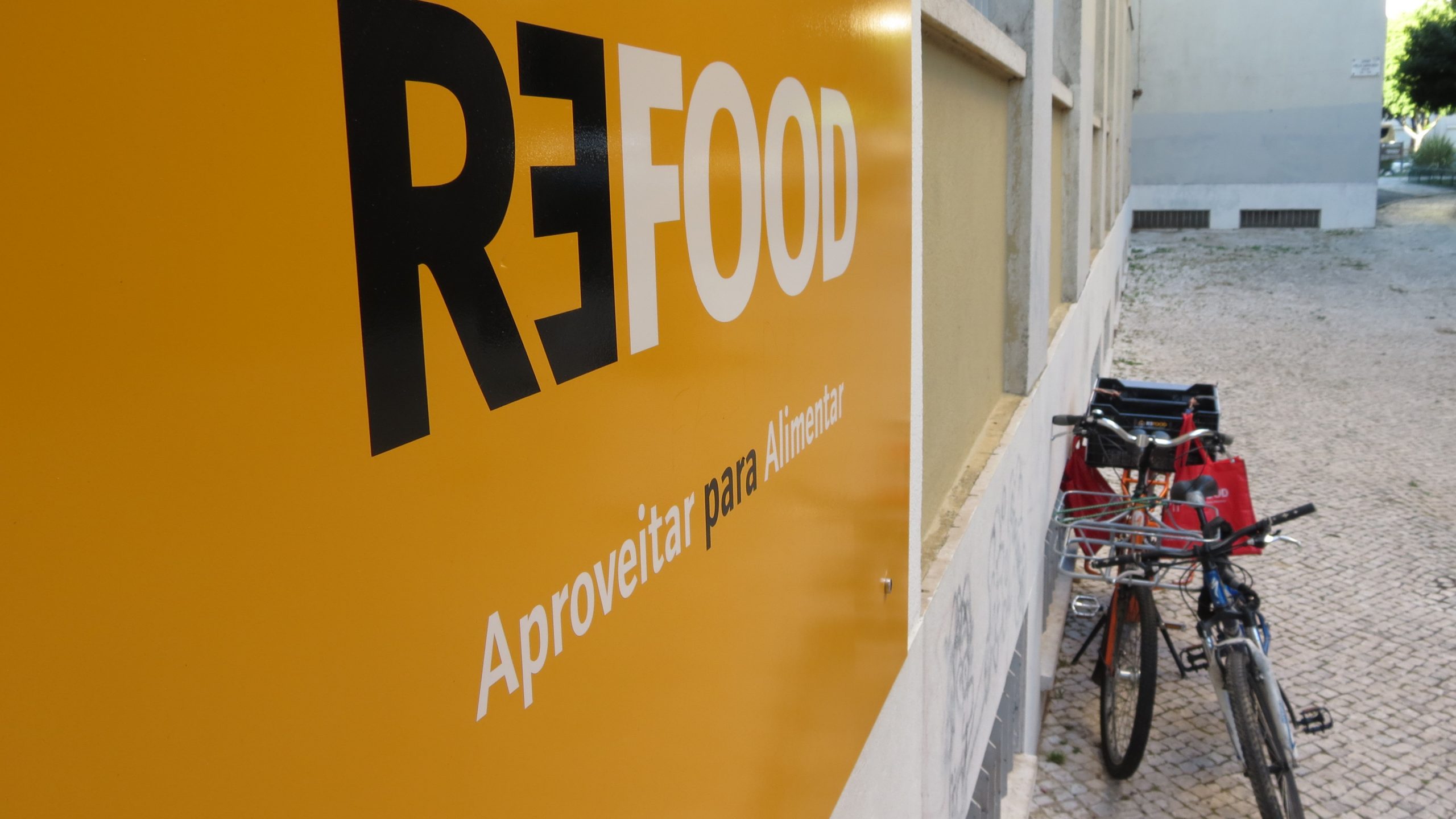 Refood's yellow sign and food collection bicycles outside a local centre